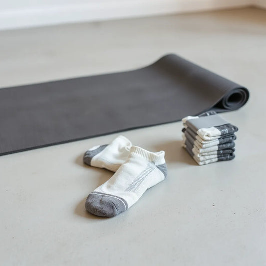 Non-slip pilates socks and a neatly stacked multipack beside a Pilates mat in a bright studio